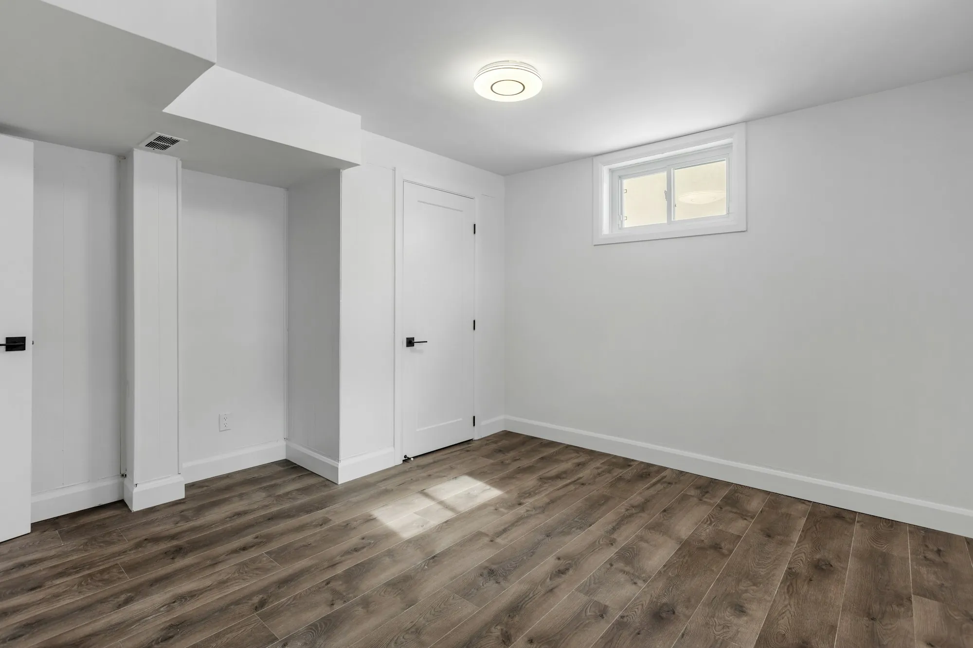 Basement guest suite with a bed, an egress window and soft lighting